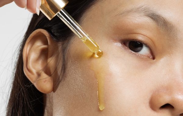 woman squirting oil down her cheek for skincare
