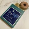 donut and dreidel plus happy hanukkah gift box. Soaps are coming out of the box on a marble background.